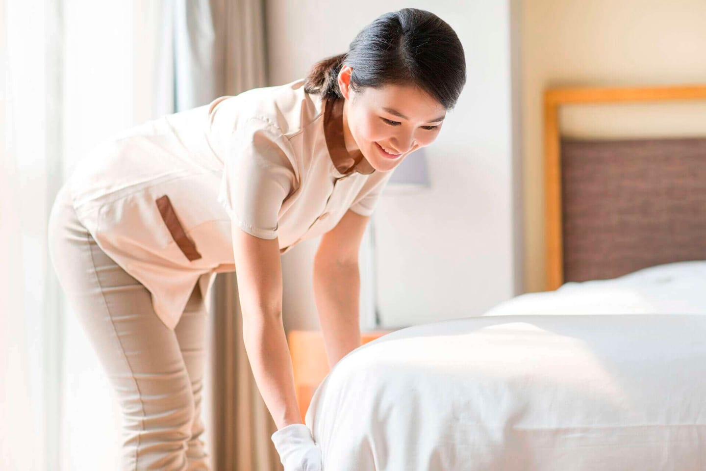 cleaning service woman tidying up and cleaning a bedroom
