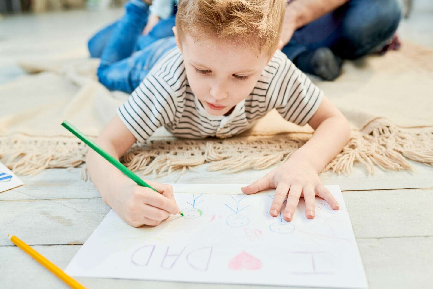 Little kid lying on a white carpet while painting