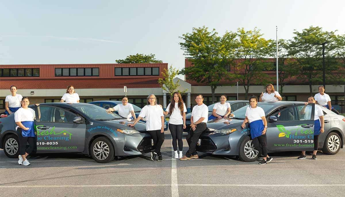 Fresh Home Cleaning team standing with branded company vehicles