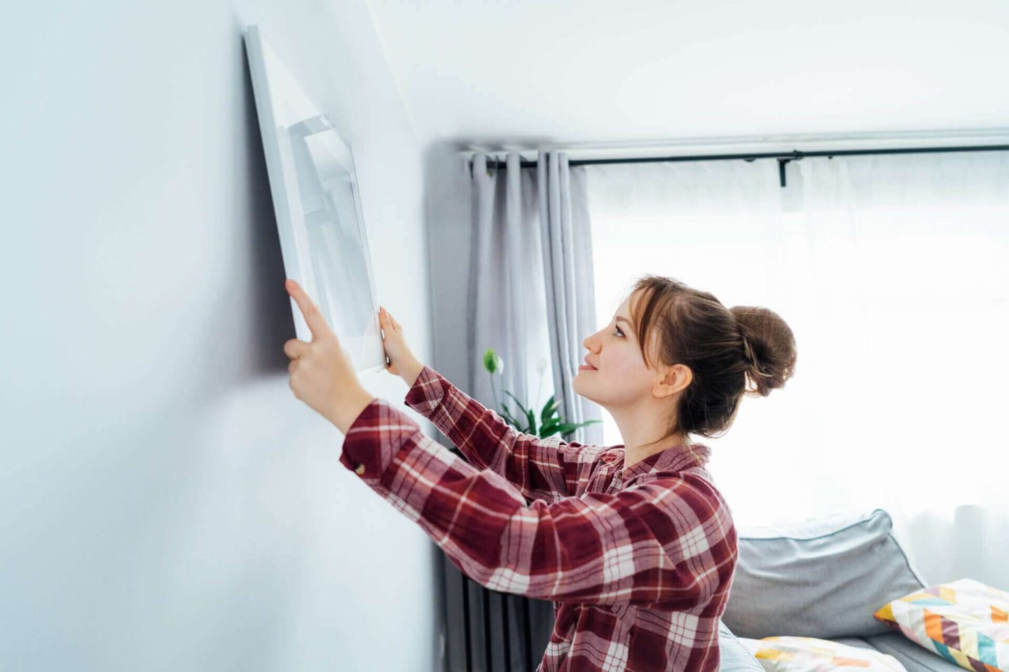 Young woman hanging a painting on her walls
